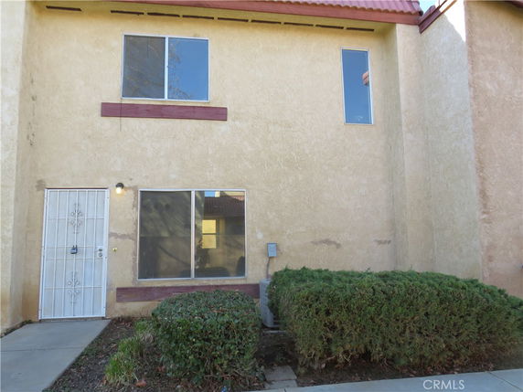 Front view of a two-story building with a metal door and large window on the ground floor and two windows on the upper floor.