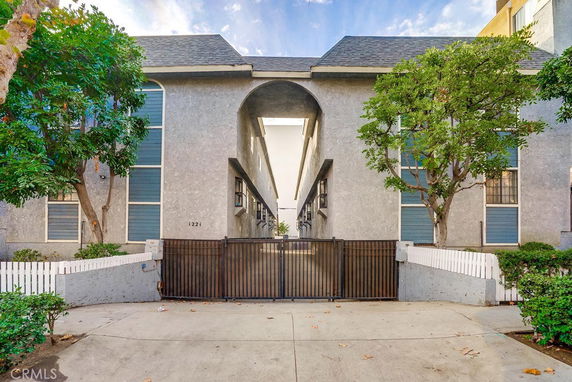 Front view of a multi-story building with a gated entrance and arched central section.