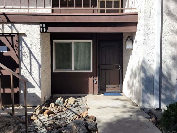 Front view of an entrance to a residential building with a brown wooden door and window.