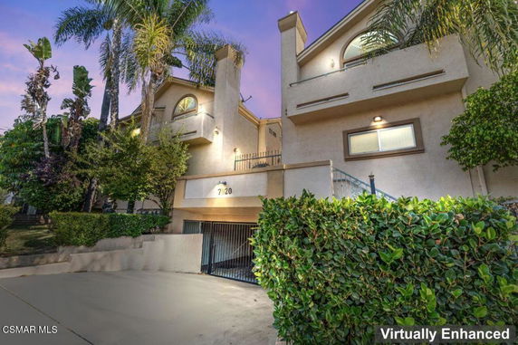 Front view of a multi-story house with a gated garage entrance and surrounding greenery.