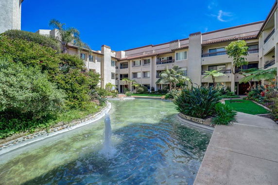 View of residential building with water feature and landscaping.