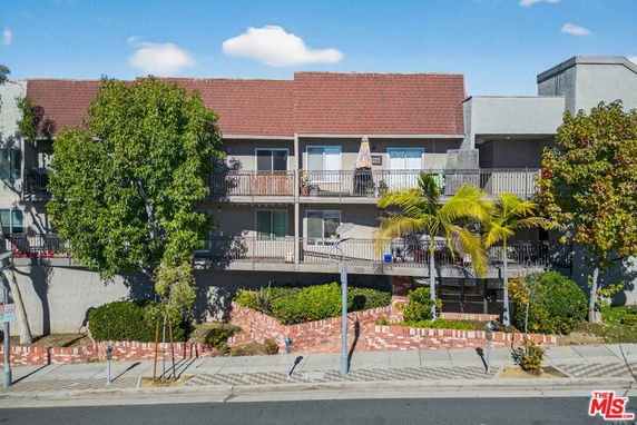 Front view of a two-story apartment building with balconies and a red roof.
