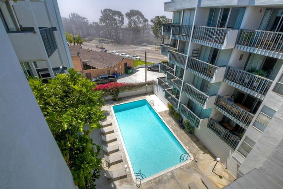 Outdoor view of a swimming pool surrounded by multi-story apartment buildings.