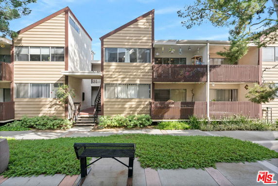 Front view of a multi-story apartment building with balconies and sloped roofs.