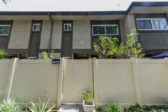 Front view of a two-story townhouse with a beige fence.