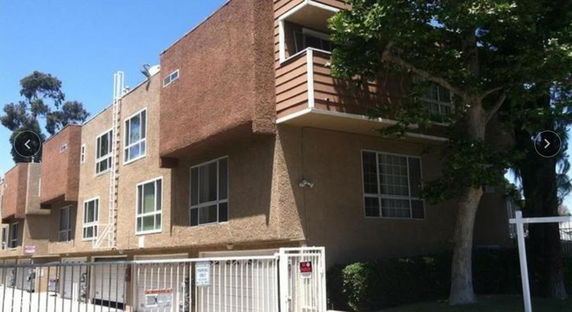 Front view of a multi-story apartment building with a balcony.