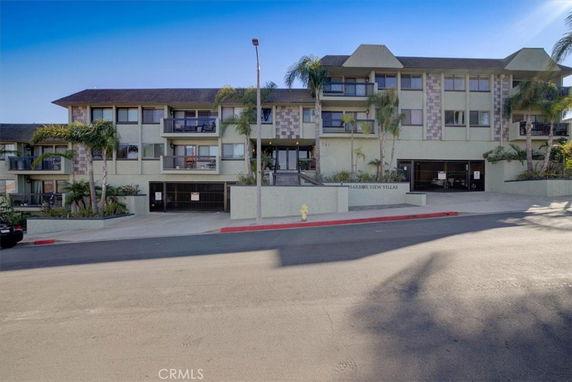 Front view of a multi-story building with balconies and palm trees.
