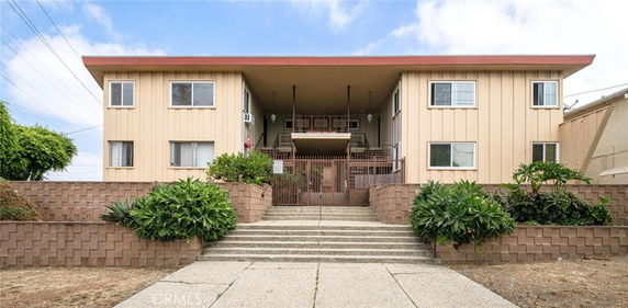 Front view of a two-story apartment building with a central entrance and stairs.