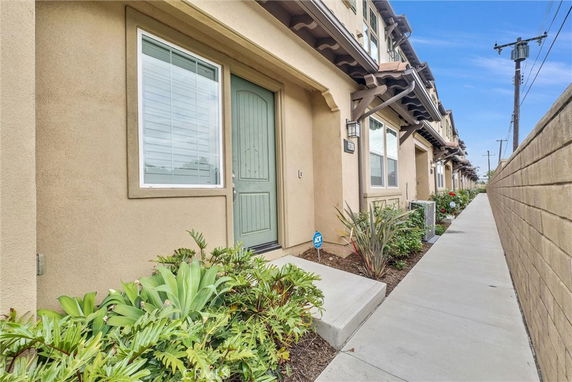 Front view of a townhouse with beige exterior and green door.