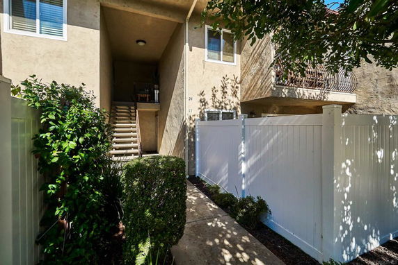 Front view of a residential building with exterior stairs and balcony.