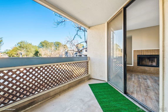 Outdoor balcony with lattice railing and a view of trees and sky.