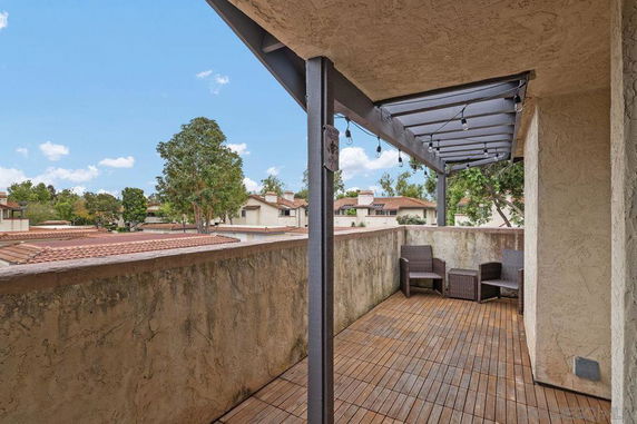 Rooftop patio with seating and string lights, overlooking residential area.
