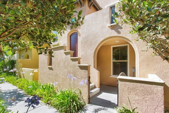 Front view of a house with arched entrance and stairs.