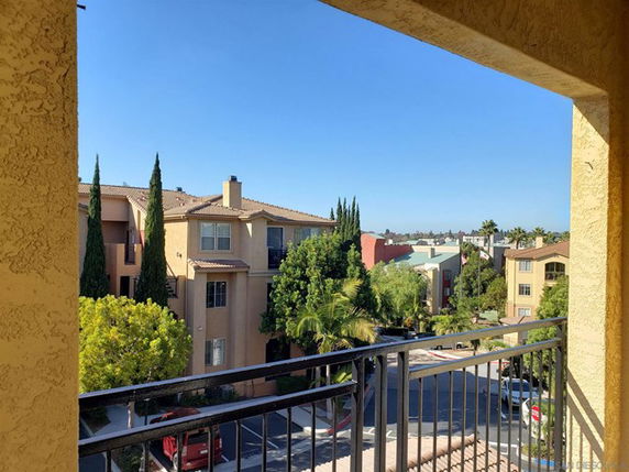 View from a balcony overlooking residential buildings and trees.