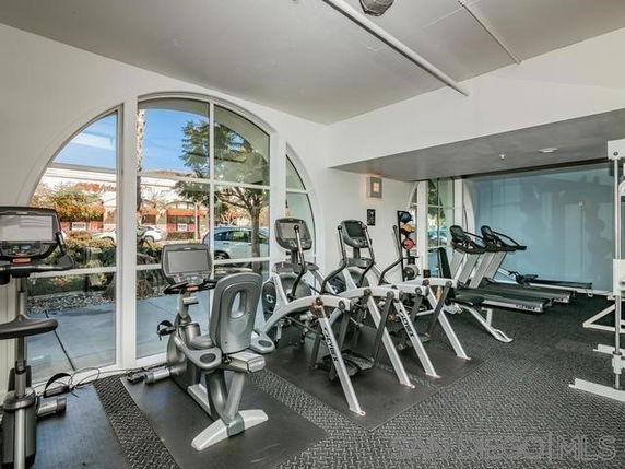 Interior view of a fitness area with exercise equipment and large windows.