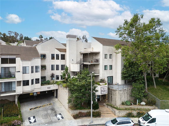 Front view of a multi-story residential building with balconies and a gated entrance.