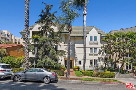 Front view of a multi-story residential building with a gable roof and balconies.