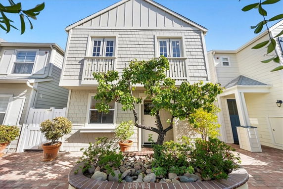 Front view of a two-story house with a brick pathway and plants in the front.