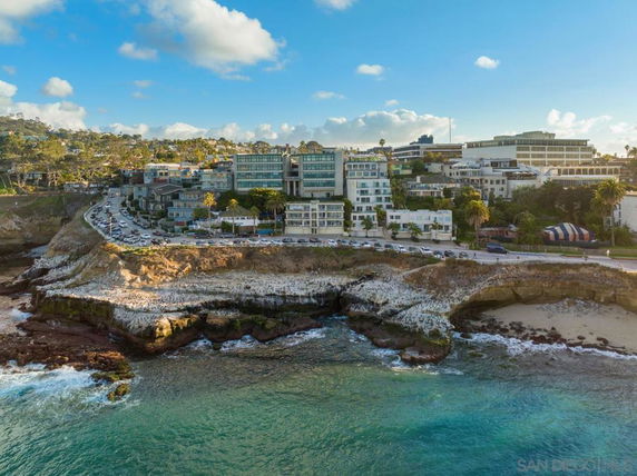 Coastal view of buildings along a cliffside with roads and vehicles.