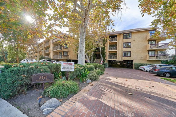 Front view of a multi-story apartment building with balconies and parking area.