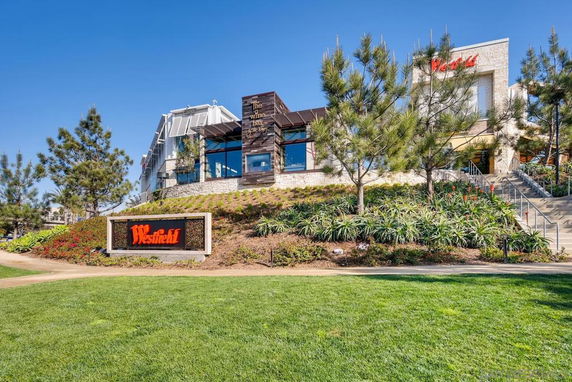 Front view of a commercial building with signage on a landscaped hill.
