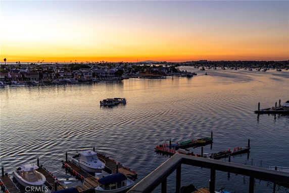 Panoramic view of a waterfront area with boats, docks, and houses at sunset.