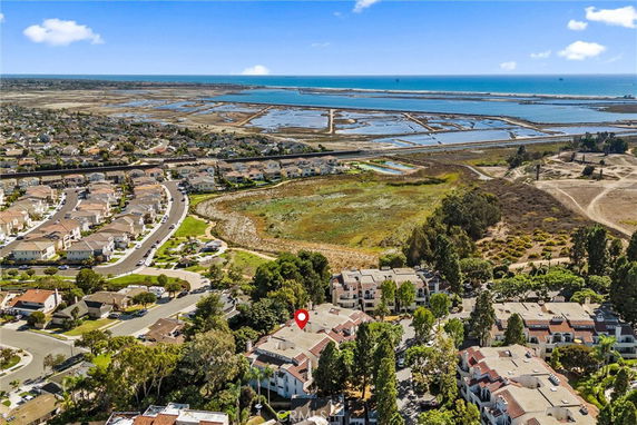 Panoramic view of residential area with houses, showing coastline and wetlands in the background.