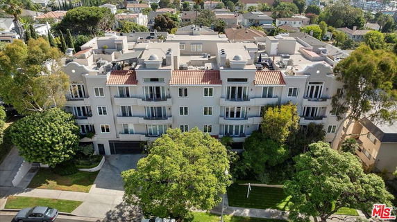 Front view of a multi-story residential building with balconies and a tiled roof.