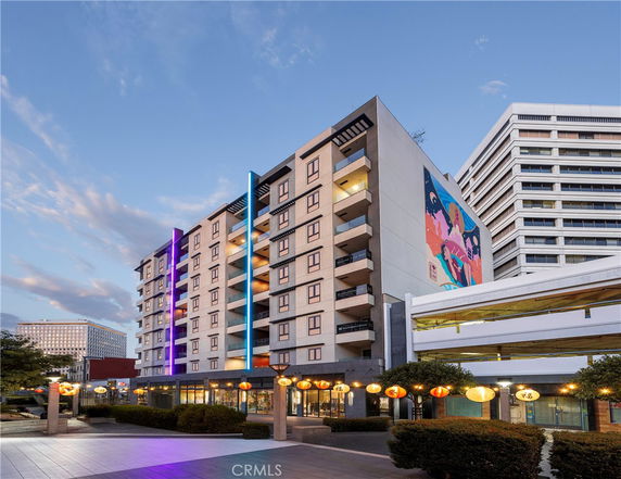 Front view of a multi-story building with colorful lighting and a mural on the side.