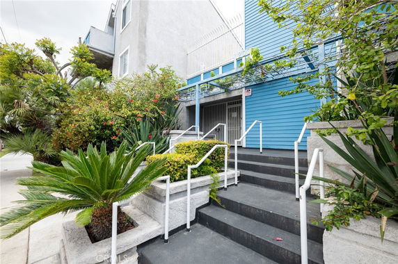 Front view of a building with blue siding and multiple steps leading to the entrance.