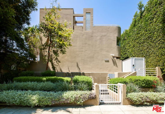 Front view of a multi-story house with minimalist design and a small garden.