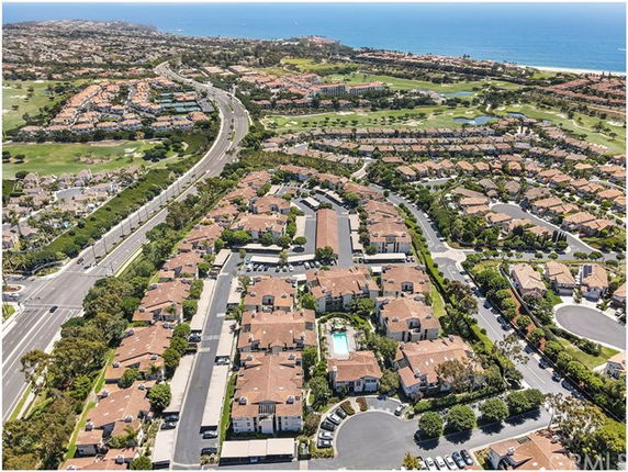 Panoramic view of a residential area with multiple buildings and roads, overlooking the ocean.