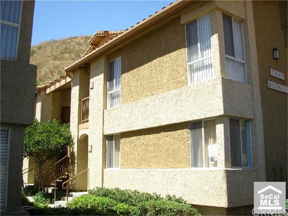 Front view of a multi-story apartment building with textured walls and large windows.