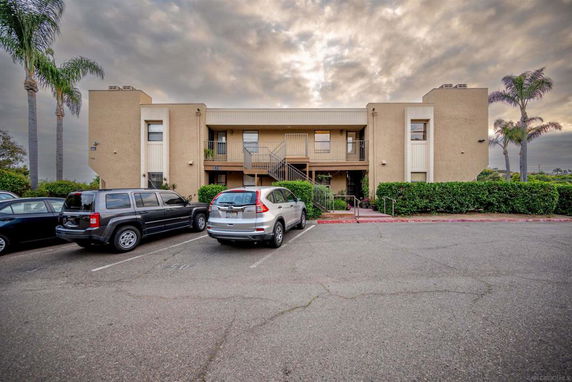 Front view of a two-story building with a central staircase and parking area in front.