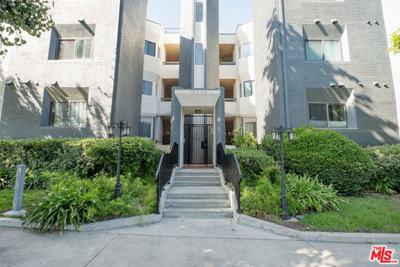 Front view of a multi-story building with a gated entrance and pathway.
