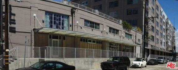 Front view of an industrial-style multi-story building with large windows and a covered entrance.