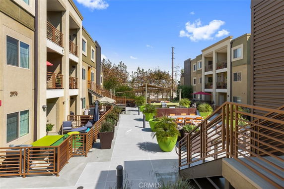Front view of a multi-story apartment complex with balconies and outdoor seating areas.