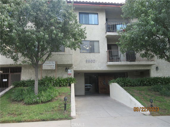 Front view of a multi-story building with balconies and a pathway leading to the entrance.