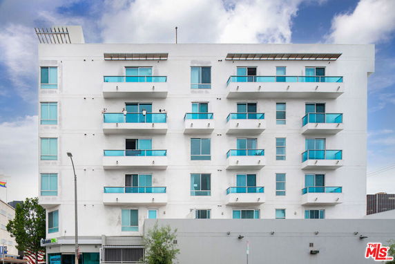 Front view of a multi-story apartment building with blue balconies.