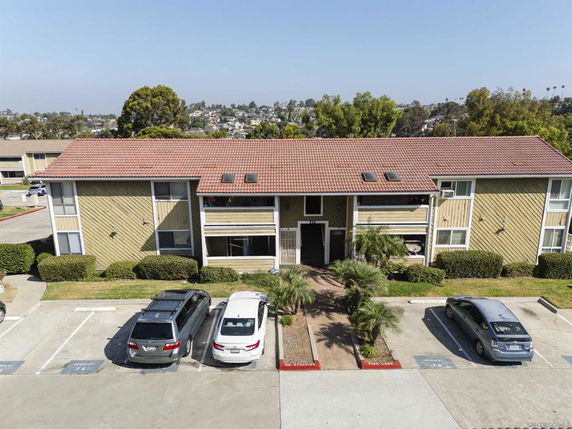 Front view of a multi-story building with a tiled roof and parking area.