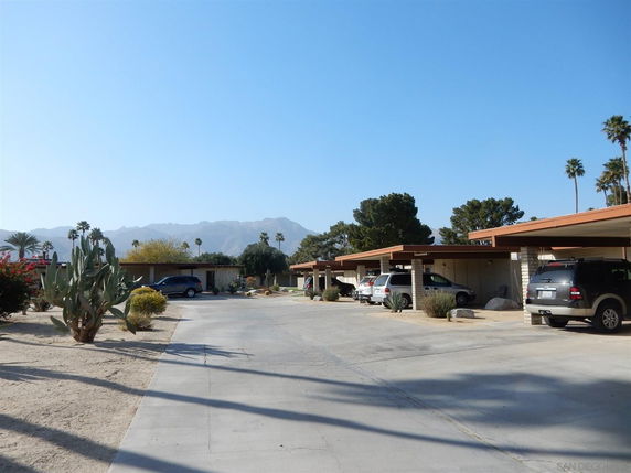 Outdoor parking area with multiple cars and covered spaces.