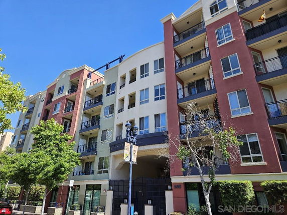Front view of a multi-story apartment building with balconies and large windows.