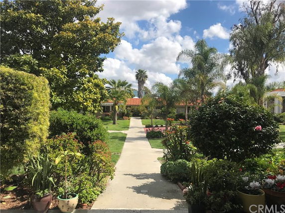 Garden path leading to buildings surrounded by trees and plants.