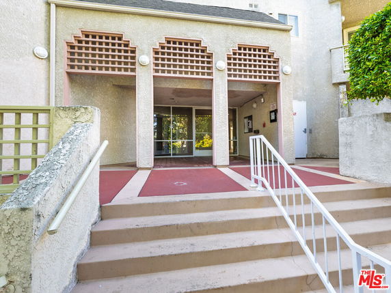 Front view of a building with a covered entrance and decorative latticework.