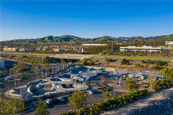 Aerial view of an outdoor skate park with a background of mountains and buildings.