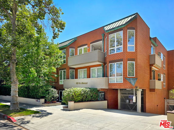 Front view of a multi-story brick apartment building with balconies and large windows.