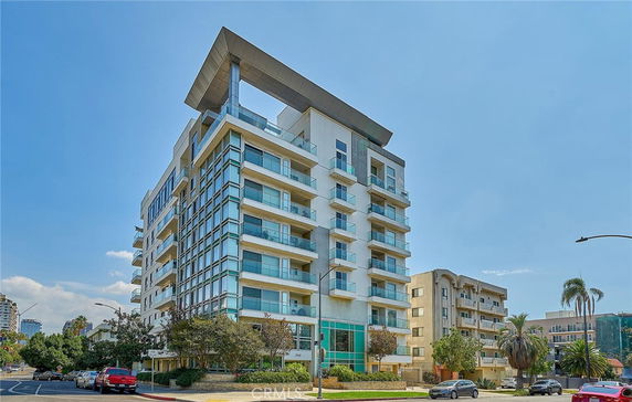 Front view of a multi-story modern residential building with balconies and large windows.