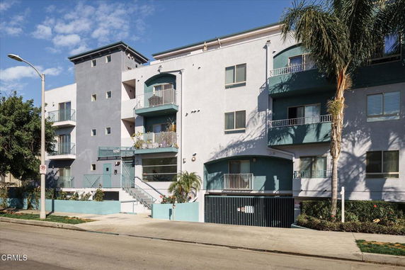 Front view of a multi-story apartment building with balconies and a garage entrance.