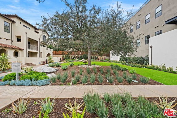 Outdoor view of a residential complex with landscaped gardens and a pathway.