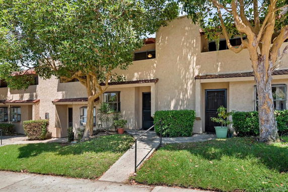 Front view of a two-story townhouse with greenery.